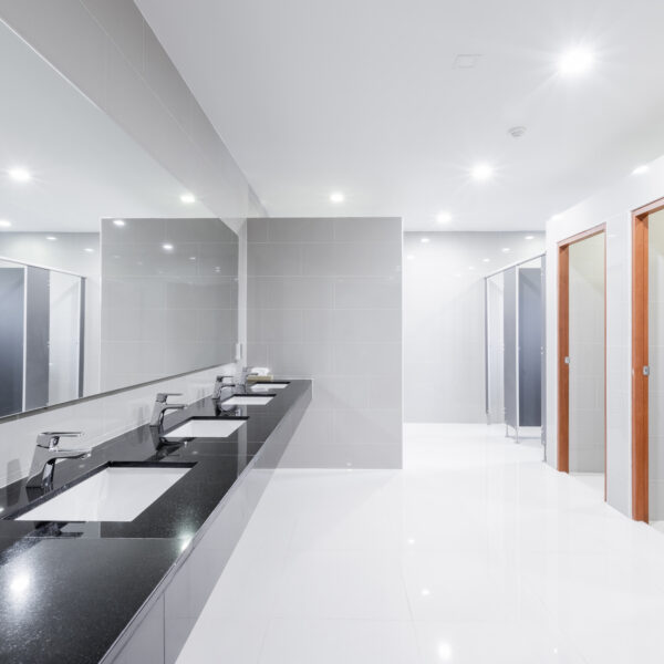 Commercial bathroom with multiple sinks in shot and multilpe toiler stalls